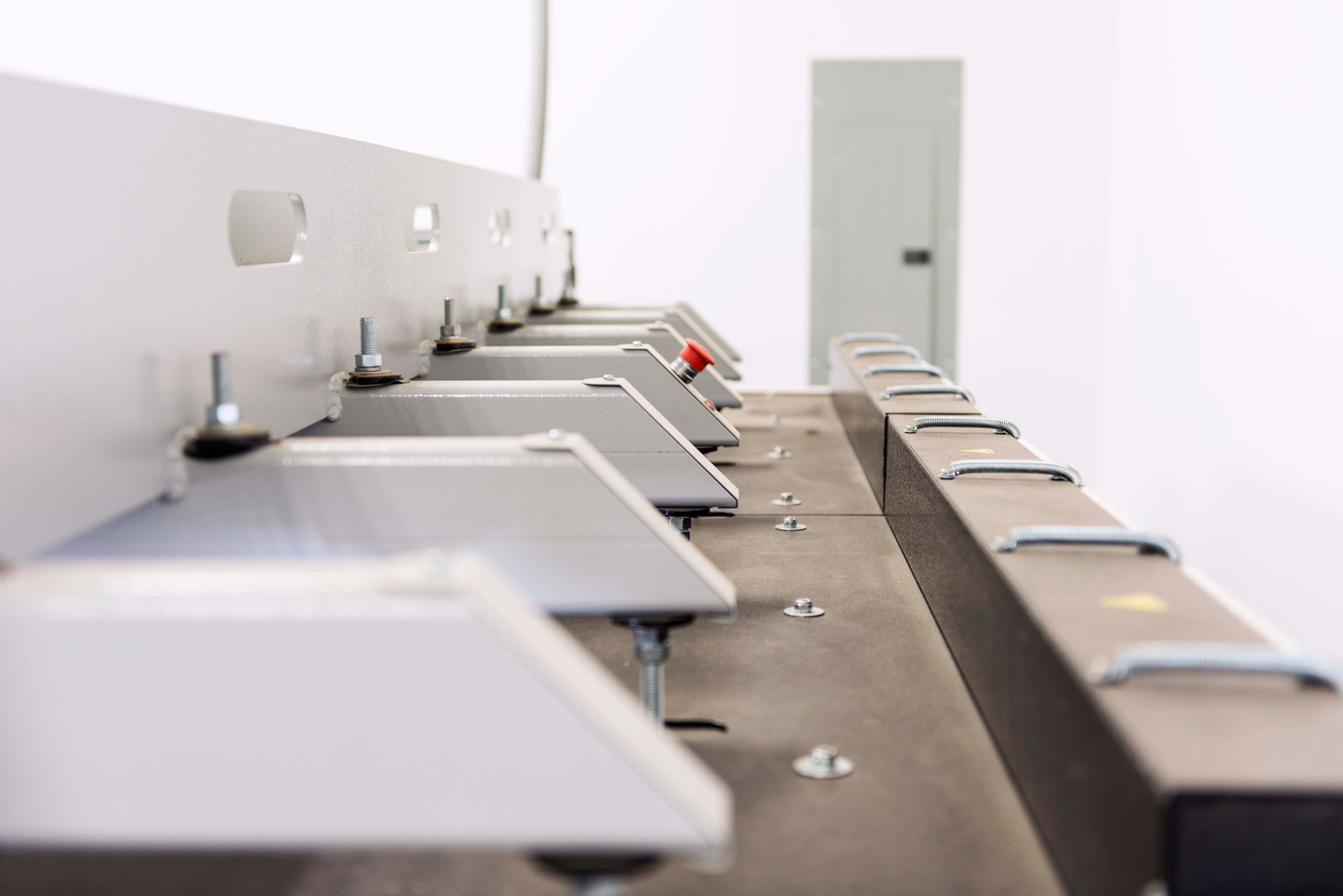 Close-up of a metal cutting machine with multiple adjustable support tables in a bright, white room.