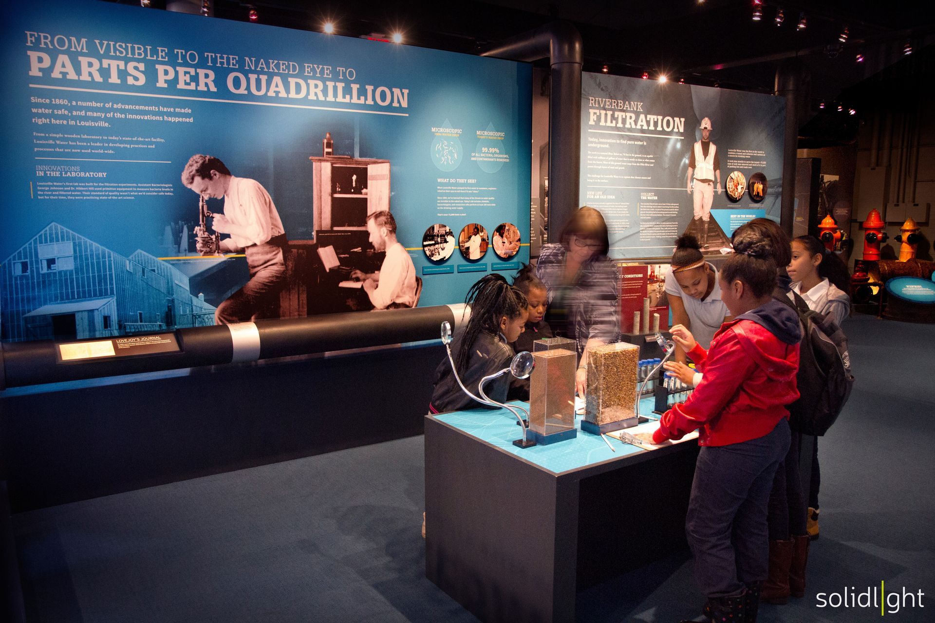 Children at a museum exhibit, examining displays and interacting with scientific information.