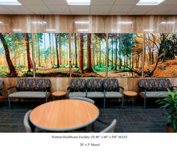 Waiting room with forest mural above chairs and round table.