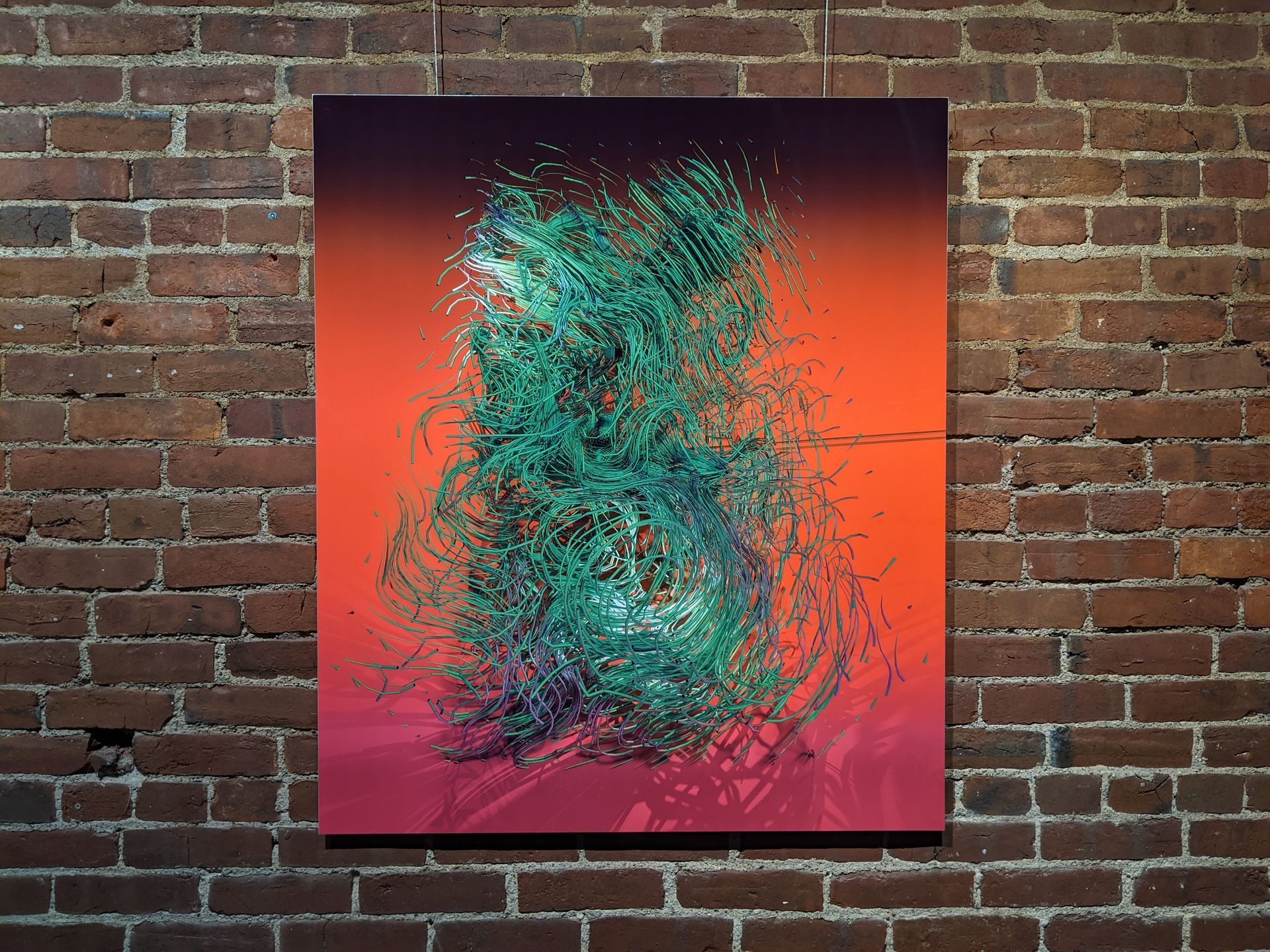 Abstract teal and orange painting on a red-brick wall.