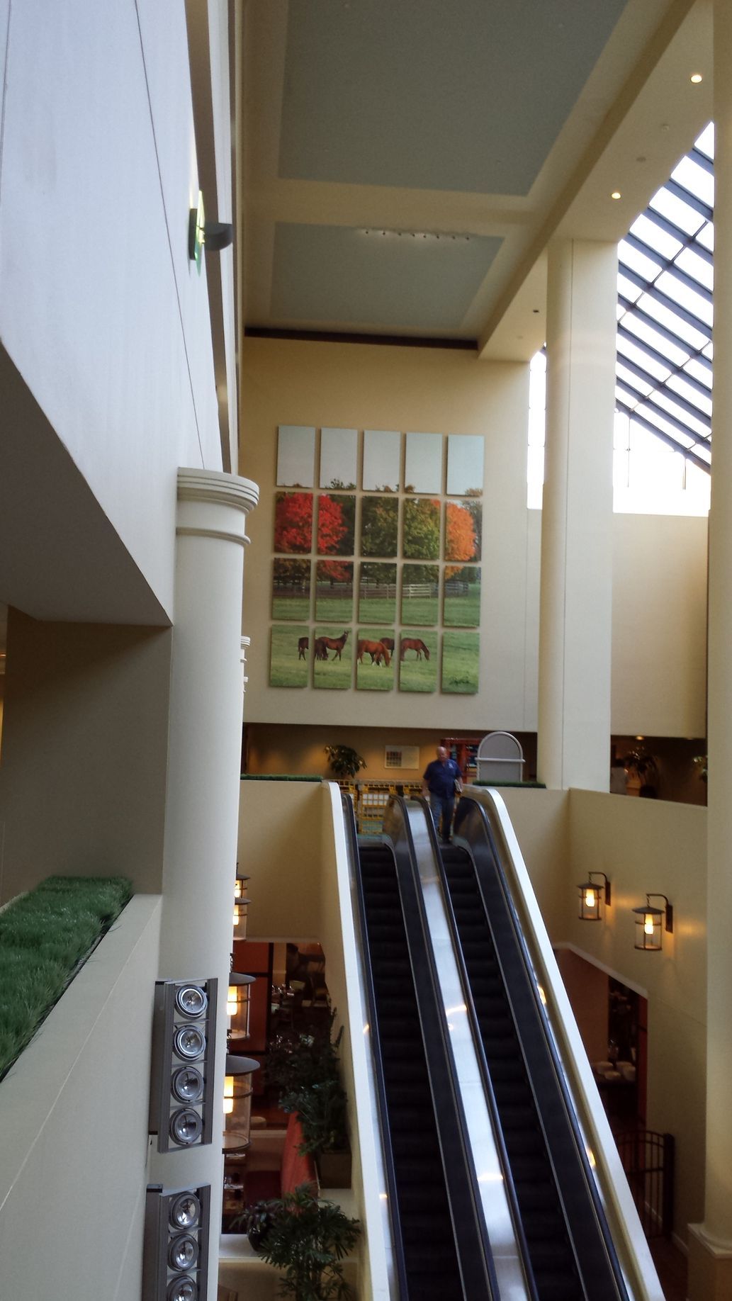 Interior with escalator and large mural of horses, high ceilings, natural light.