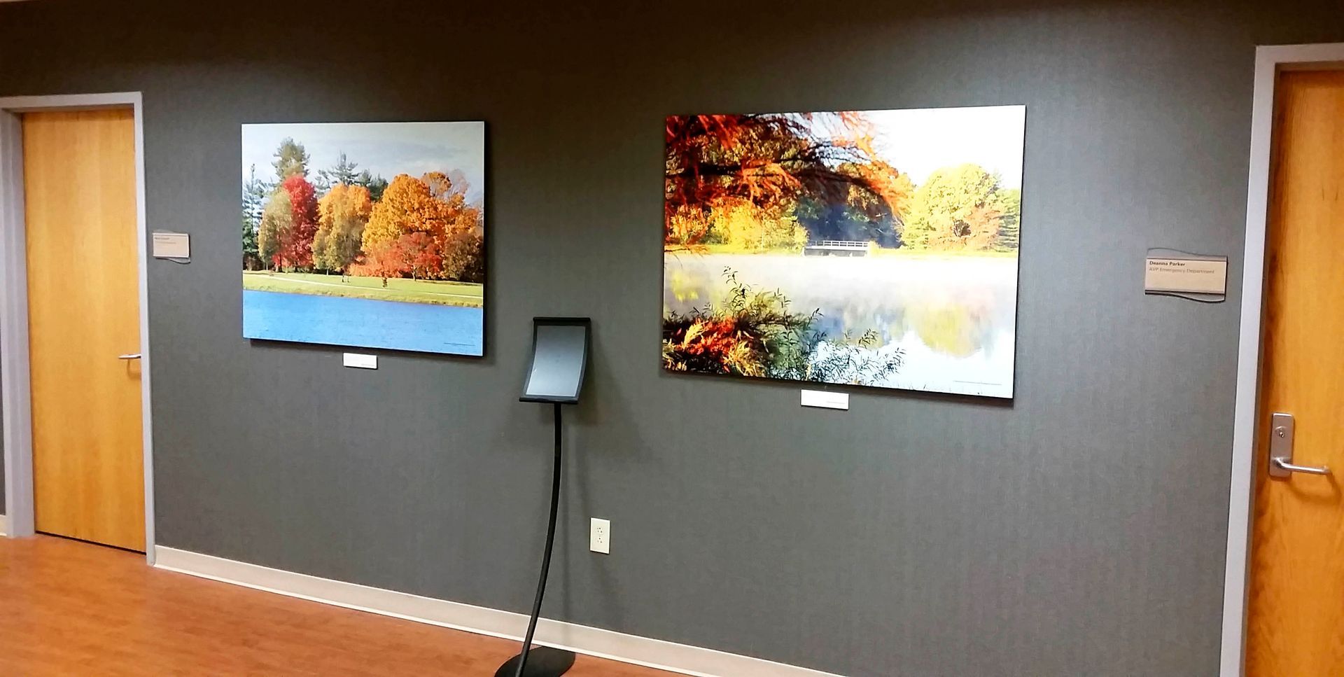 Two landscape paintings with fall foliage hang on a gray wall in a hallway.