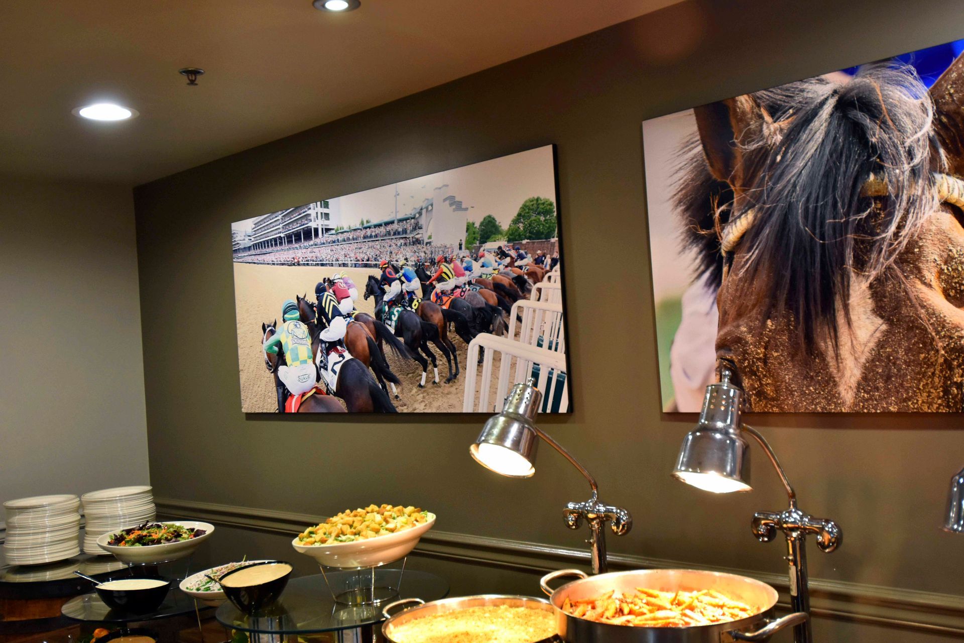 Buffet with food and horse racing artwork on a wall.