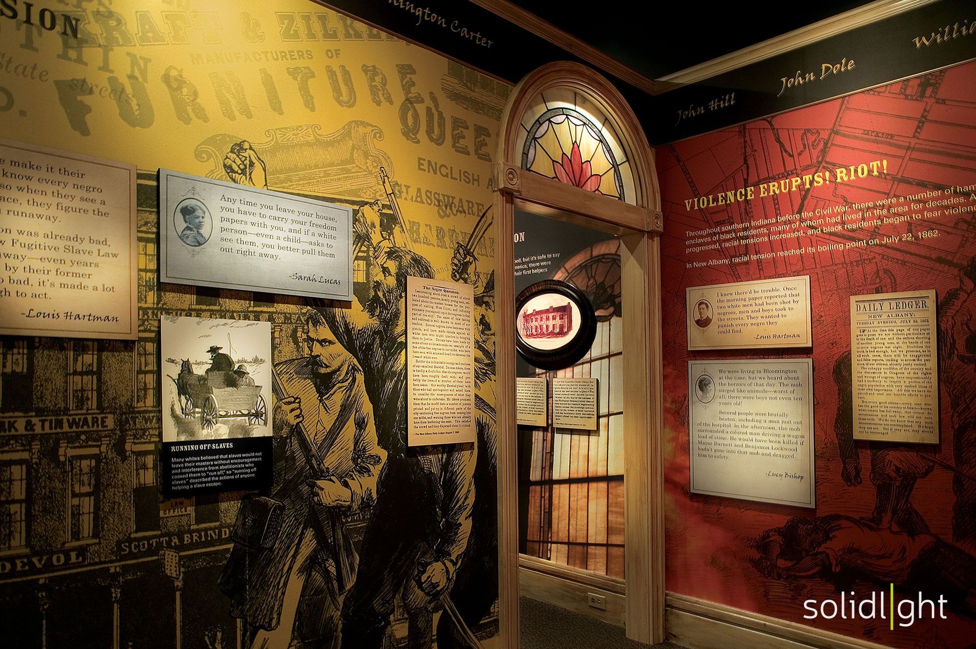 Museum display with historic documents on walls, illuminated doorway, warm tones.