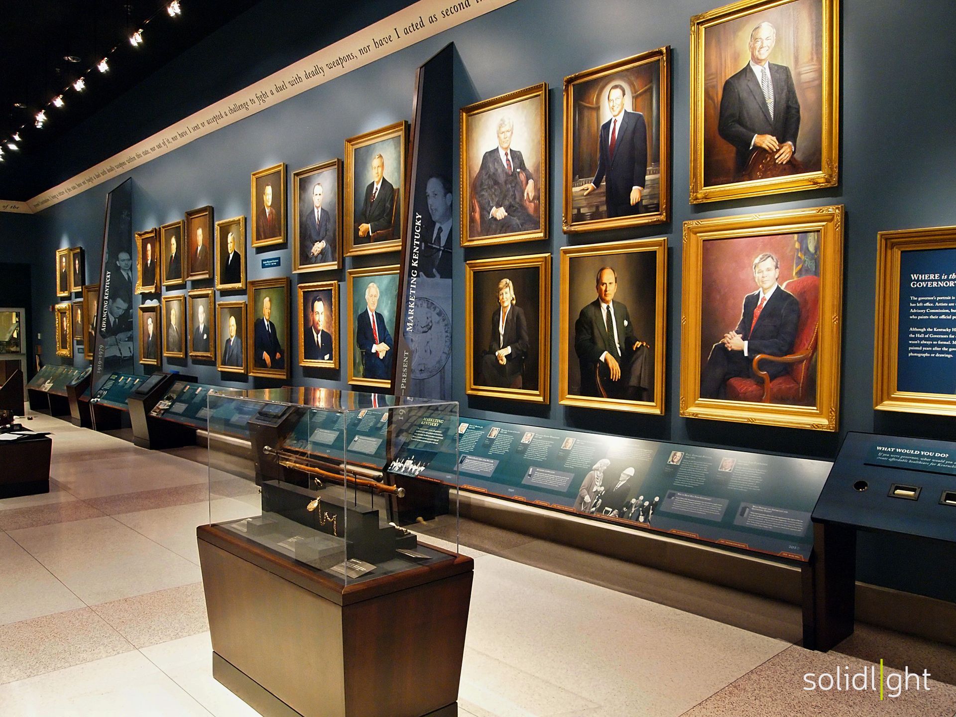 Museum hall with portraits, display cases, and artifacts.