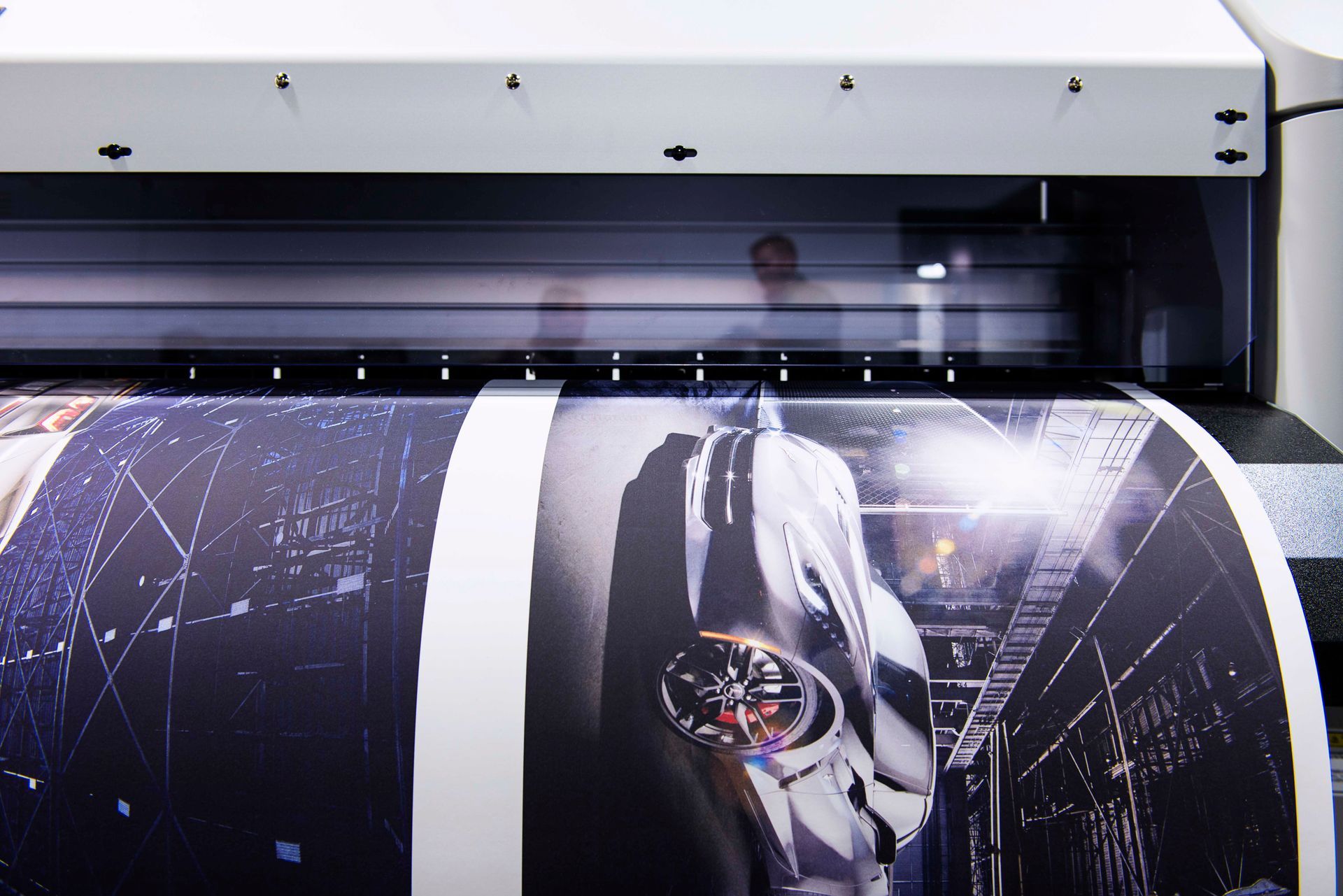 Large format printer printing a poster with a photograph of a person in a futuristic setting.