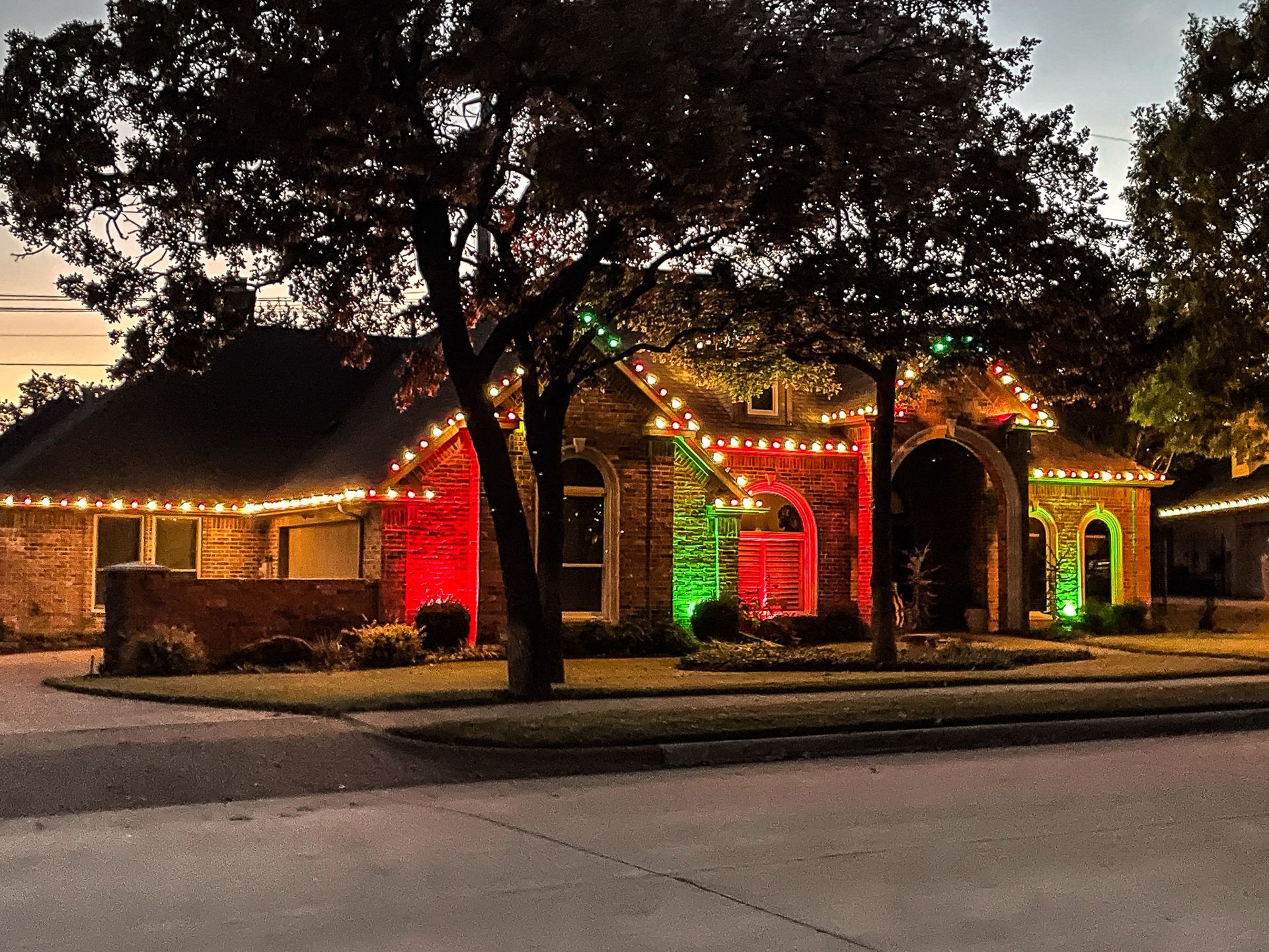 House decorated with Christmas lights; red and green spotlights illuminate the front.