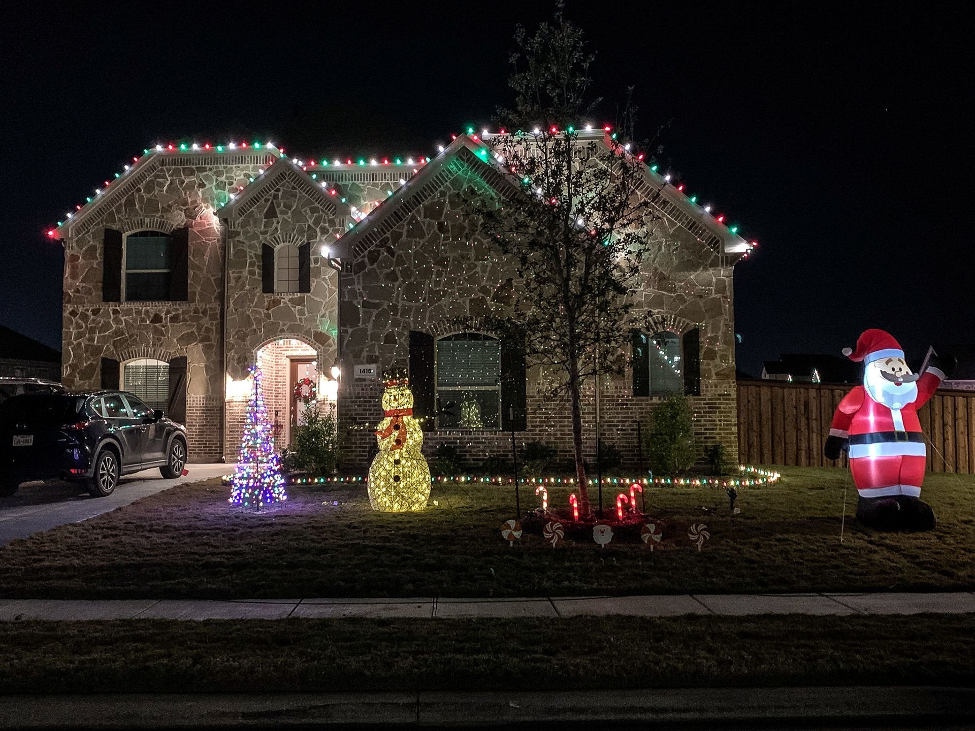 House with Christmas lights and decorations at night, including an inflatable Santa.