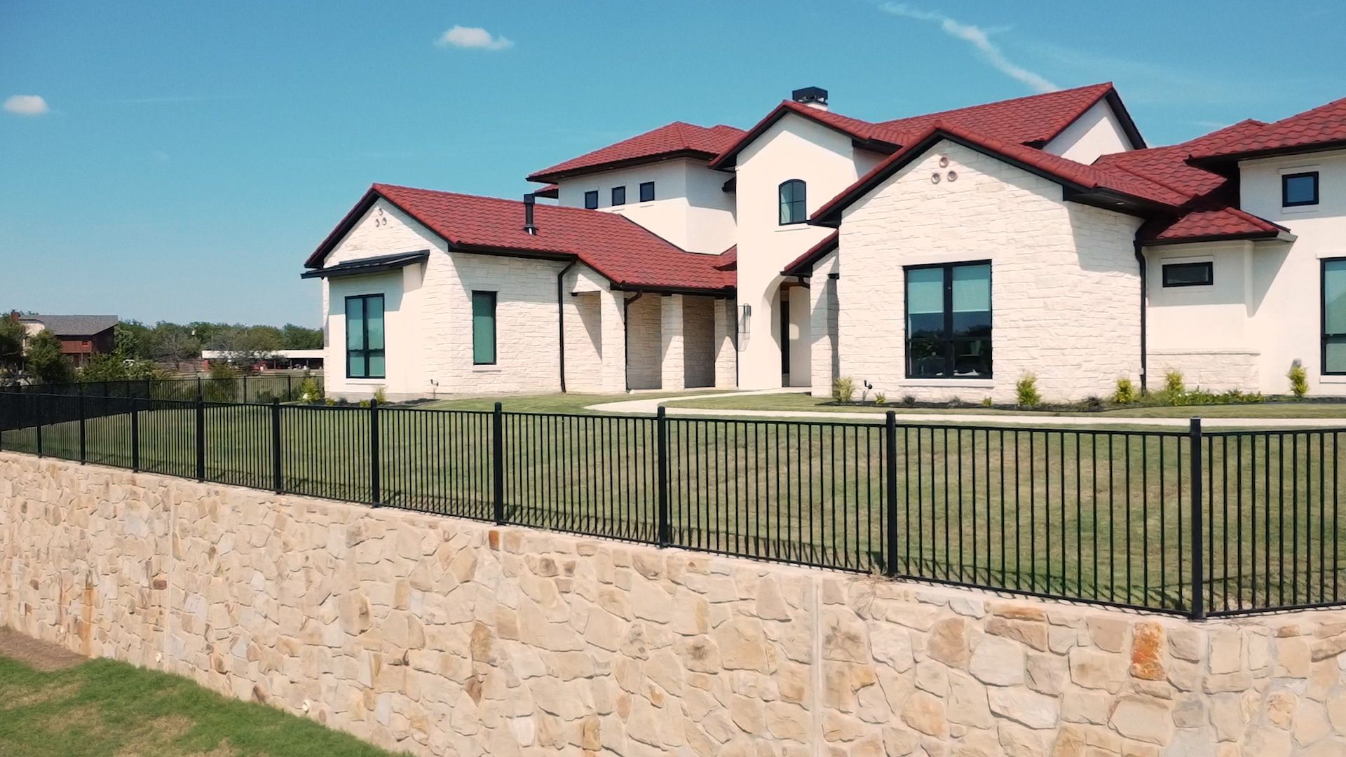 Black plastic panels stacked on a wooden trailer, likely for construction. A grassy hill with houses is in the background.