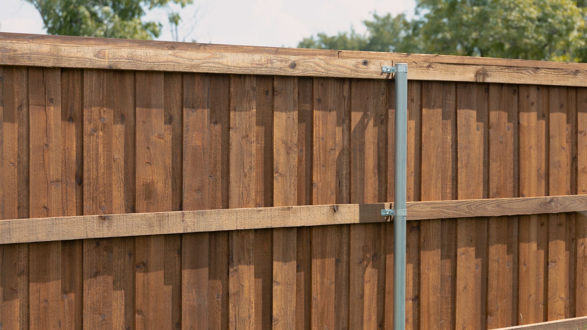 Brown wooden fence with a silver post.