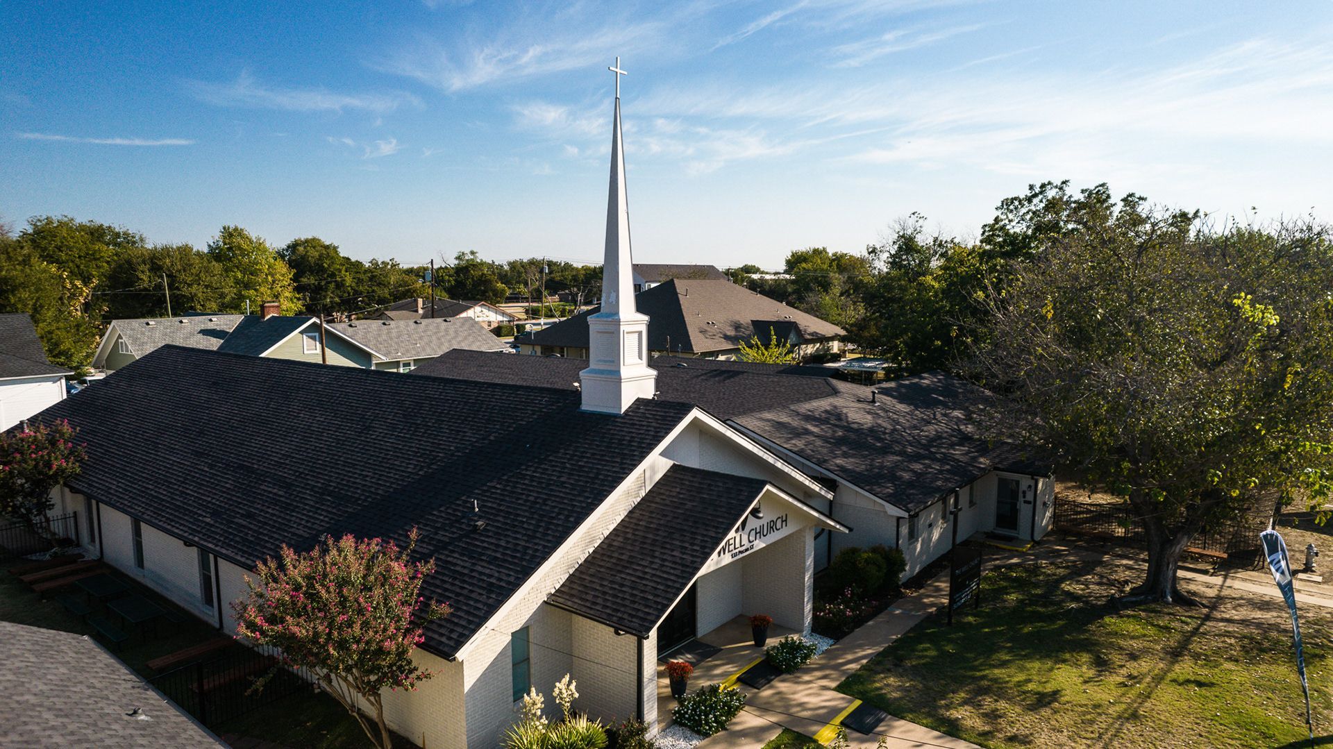 Church building with white facade and steeple against a blue sky.