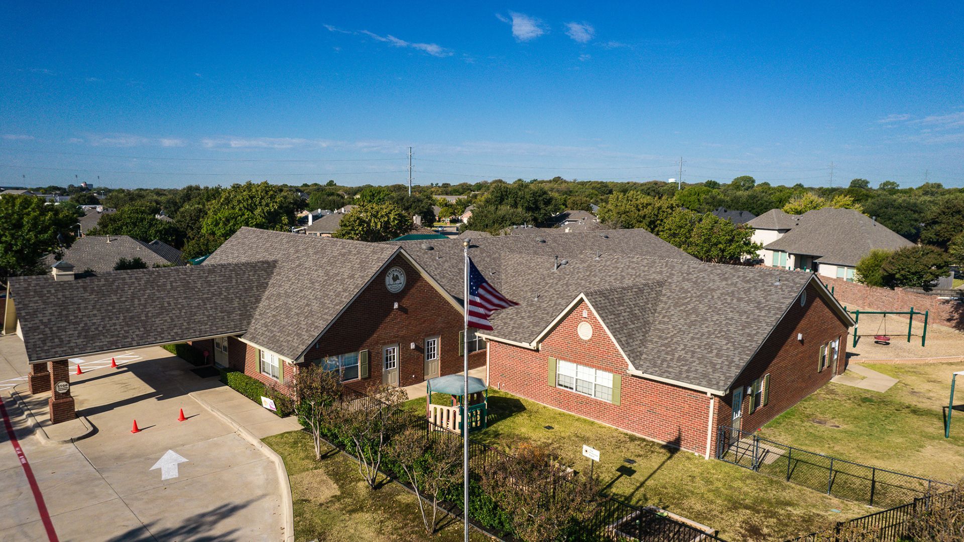 Brown building with American flag, trees, and blue sky.