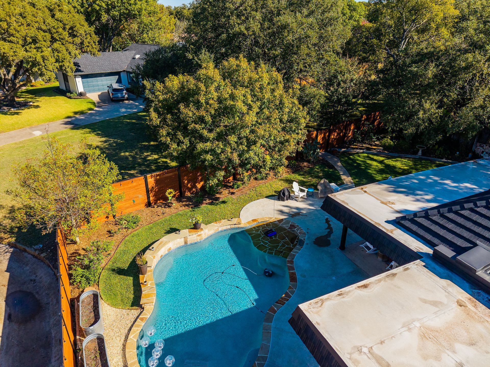 Black fence in front of a large white house with a red roof, under a bright blue sky.