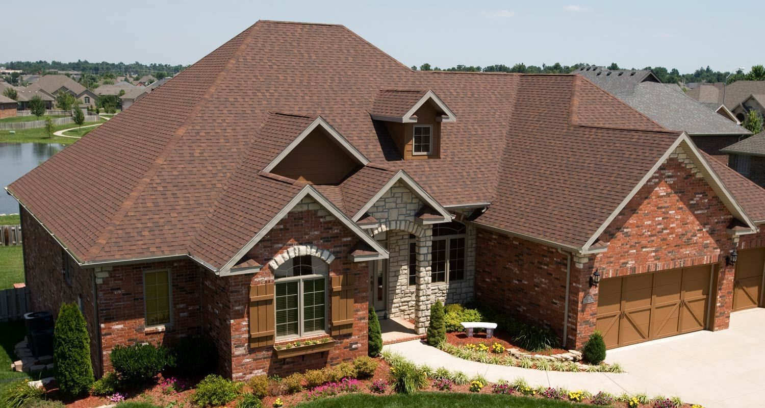 A large brick house with a brown roof and a large driveway
