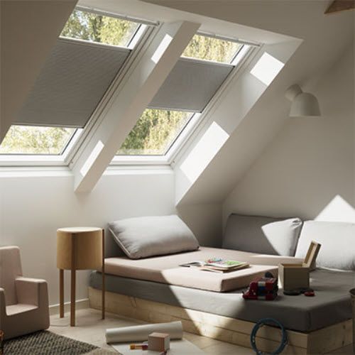 A living room with a couch and a chair under a skylight.