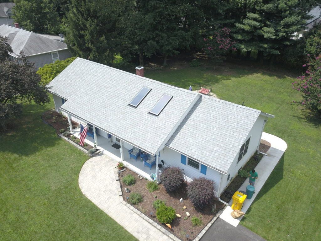 An aerial view of a house with a gray roof and a porch.