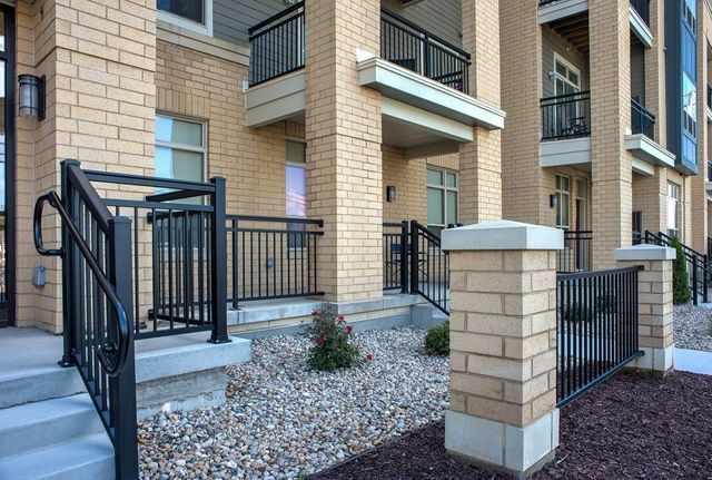 A brick building with a black railing and stairs in front of it.