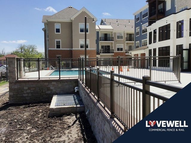 A fence surrounds a swimming pool in front of a building.