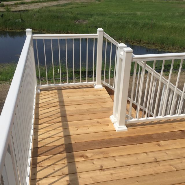 A wooden deck with a white railing overlooking a body of water