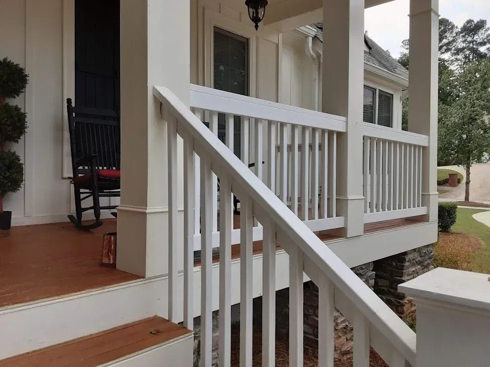 White porch with railing and steps leading up to the front door of a house.