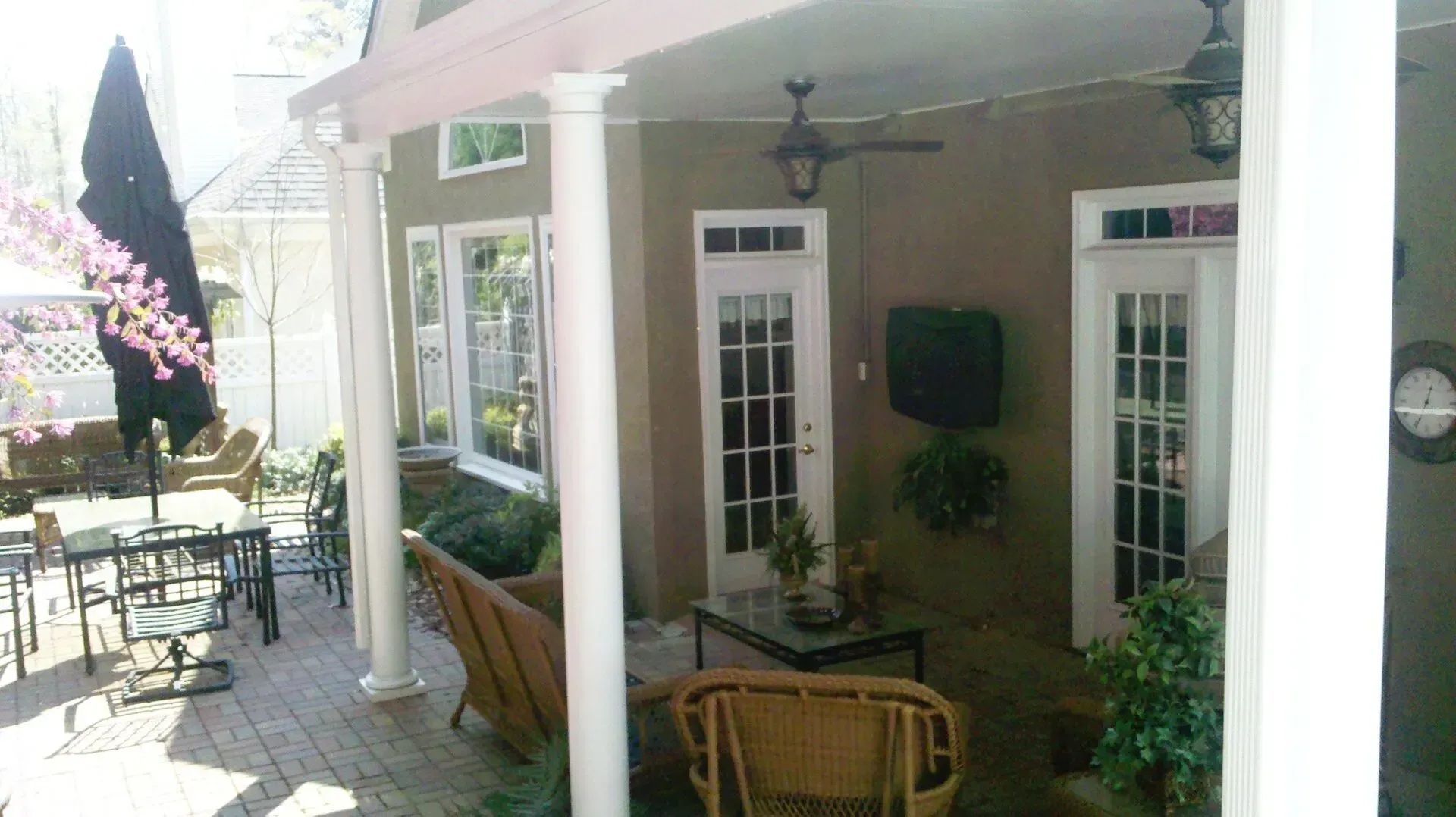 Patio with seating, doors, and a decorative umbrella. The walls are neutral in color, with white columns.