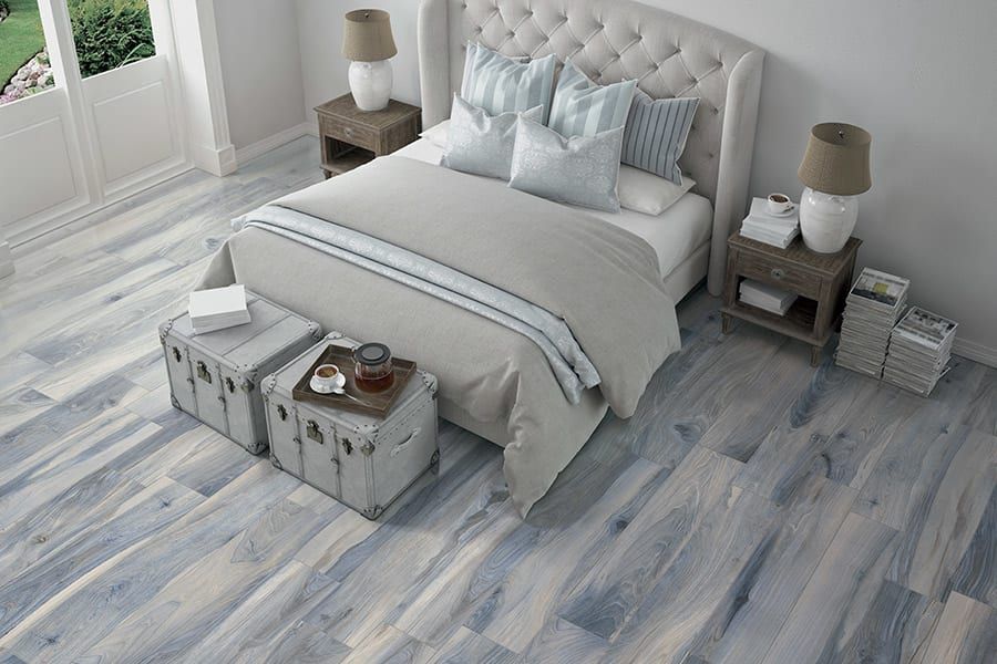 A bedroom with a bed , nightstands , lamps and a wooden floor.