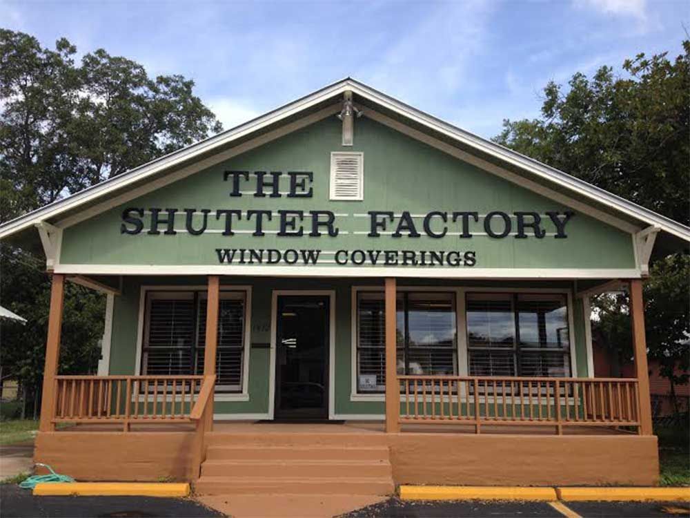 A green building with the words the shutter factory window coverings on it