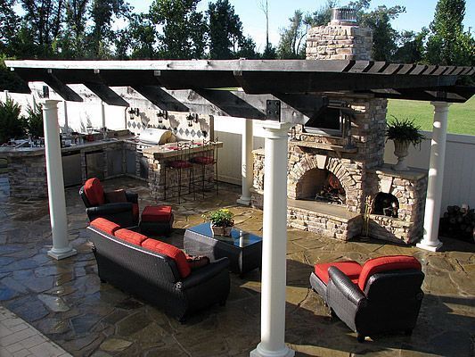 Outdoor living space with pergola, fireplace, and seating area.