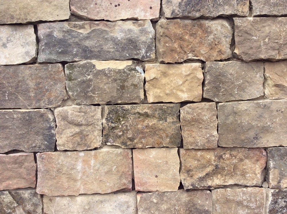 Stone brick wall with tan, brown, and gray hues.