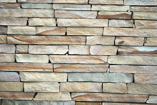Stone wall composed of rectangular, beige, and tan blocks.