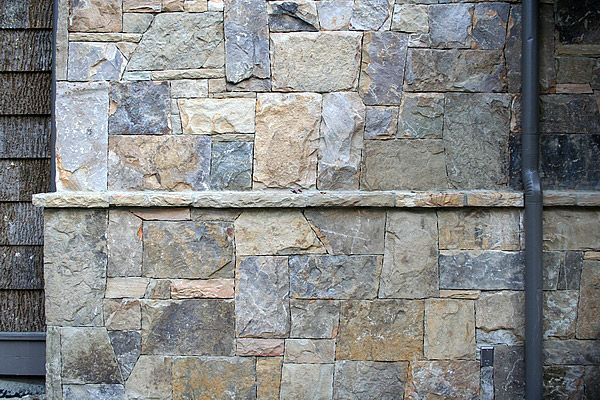 Stone wall with a horizontal stone trim; brown, gray, and tan.