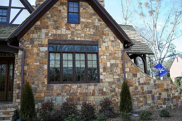Stone exterior of a house with a brown roof and a window.