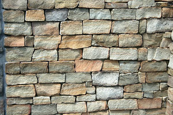 Stone brick wall with varied colors of tan, gray, and pink.
