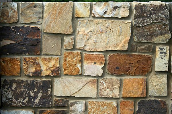Stone wall made of various sized, rectangular, and colorful stones with grey mortar.