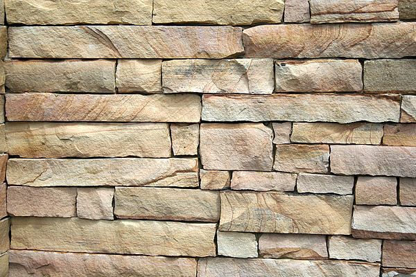 Stone wall with rectangular, tan and brown stones.