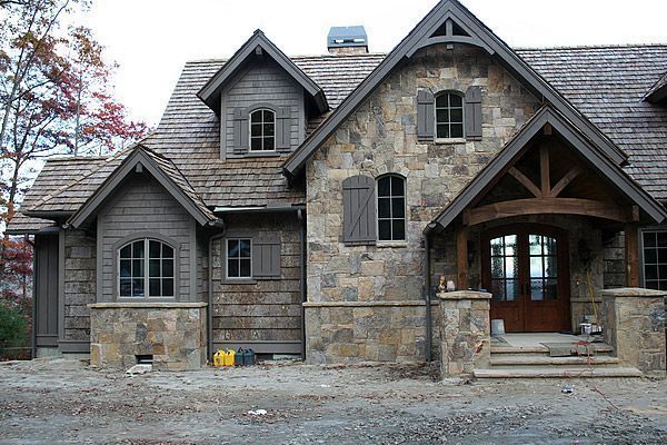 Stone and wood cottage with dormers, shutters, and an arched entryway.