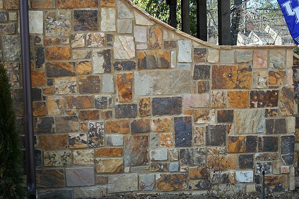Stone wall with a mix of brown, tan, and gray rectangular stones.