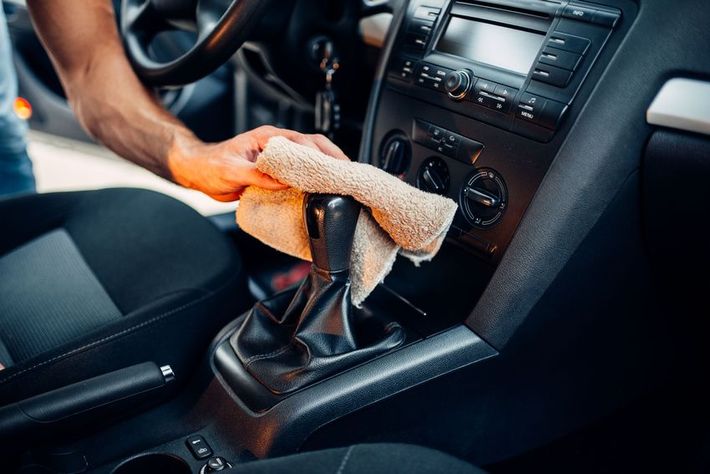 A man is cleaning the interior of a car with a towel.