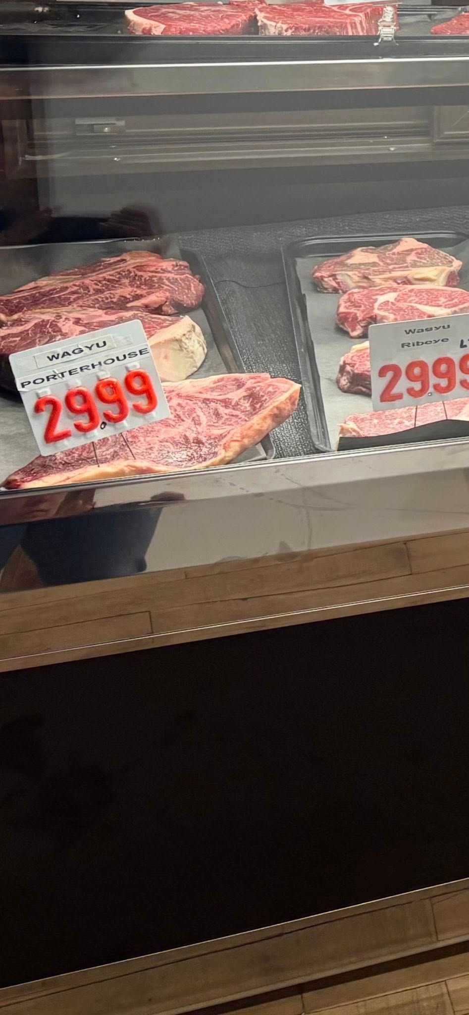Meat display case with steaks, price tags show $29.99.