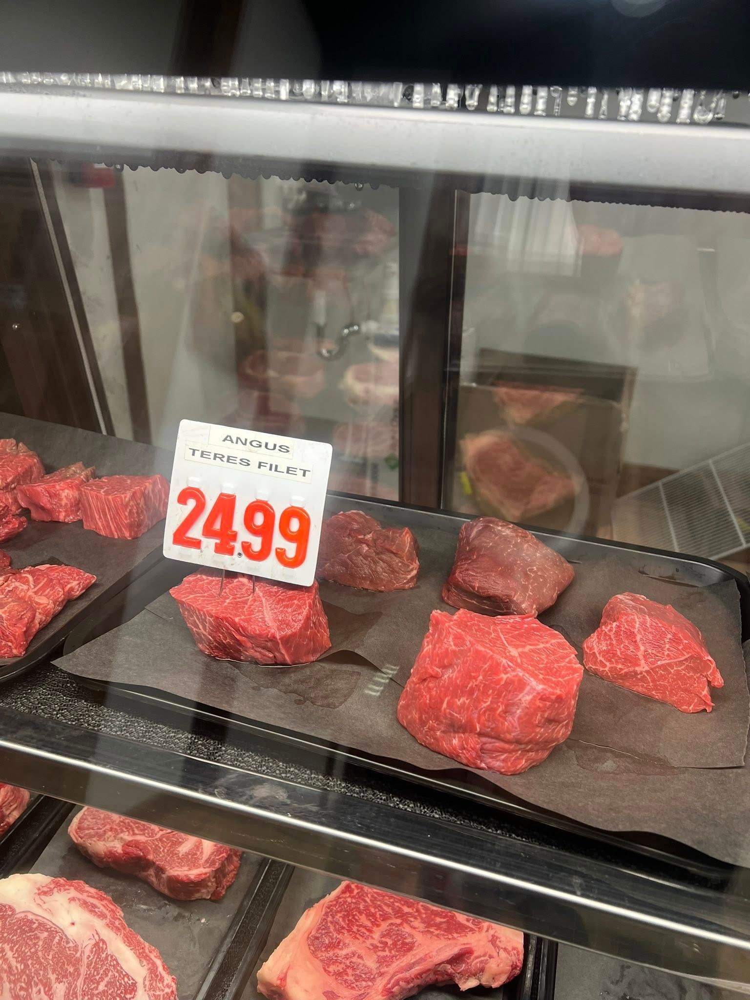 Meat display case with cuts of raw beef, price tag reads 24.99.