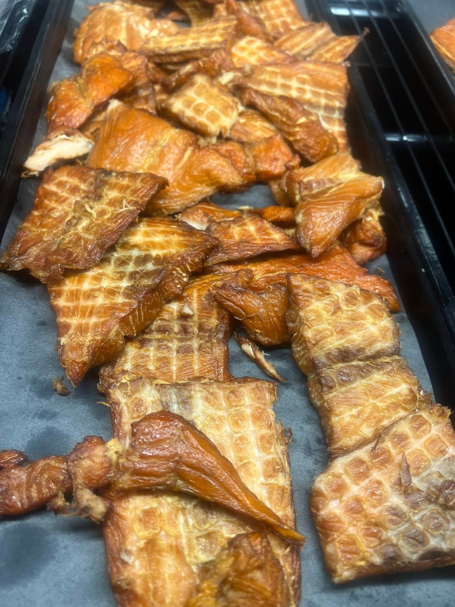 Smoked salmon, rectangular and waffle-patterned, piled on a tray; various shades of brown.