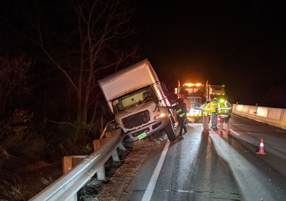 Truck crashed into guardrail on dark highway, with emergency responders and flashing lights nearby