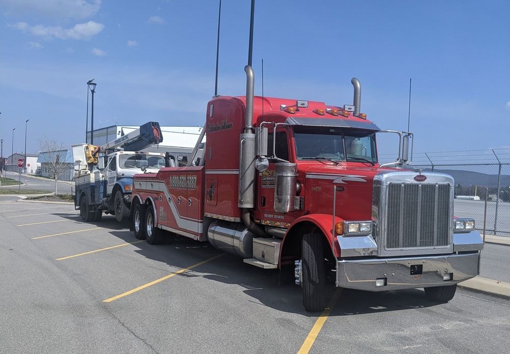 Red semi-truck hauling a flatbed trailer parked in a lot under a clear sky