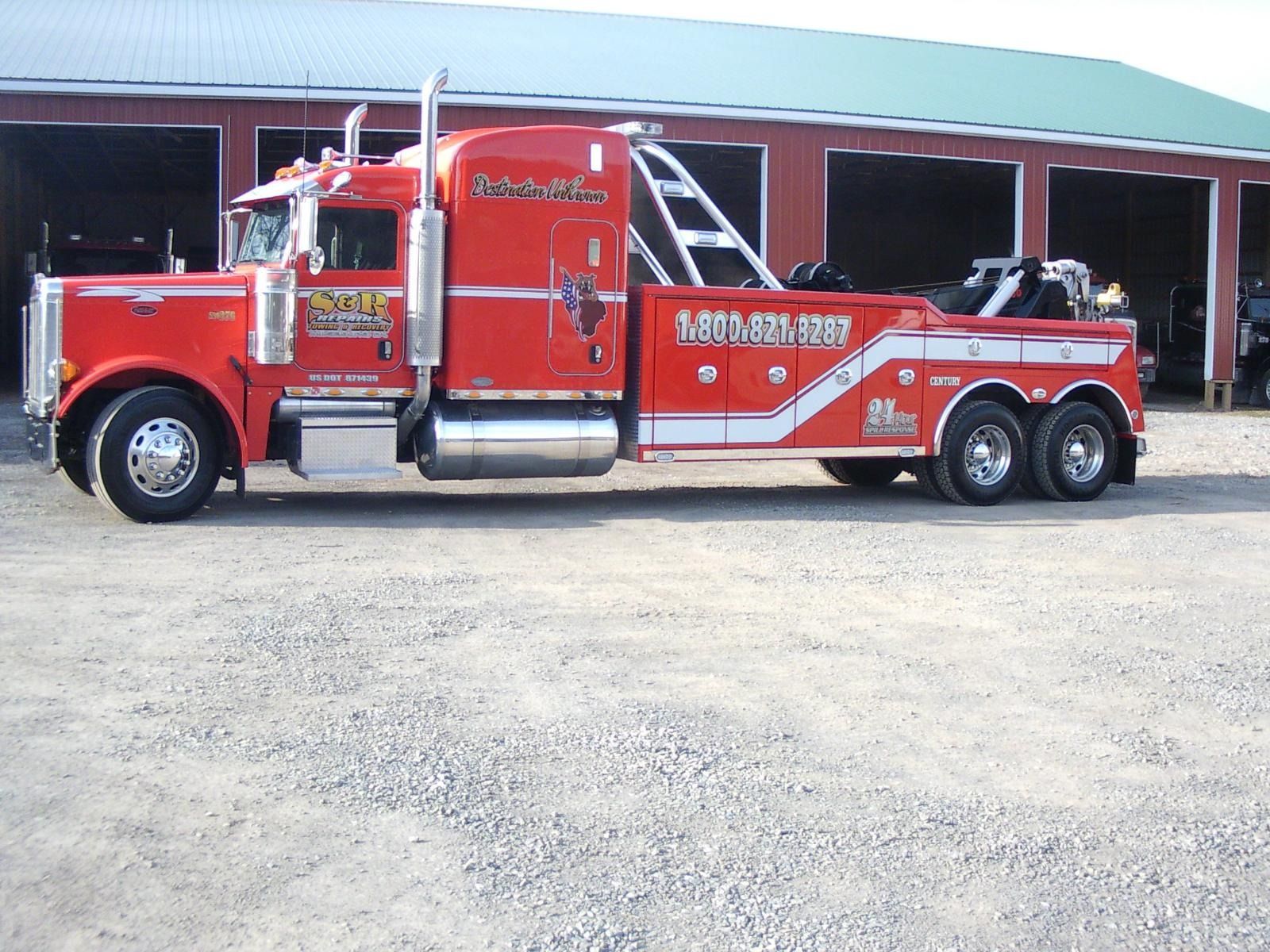 Red classic fire truck parked in front of a fire station, side view.