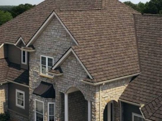 An aerial view of a large brick house with a brown roof