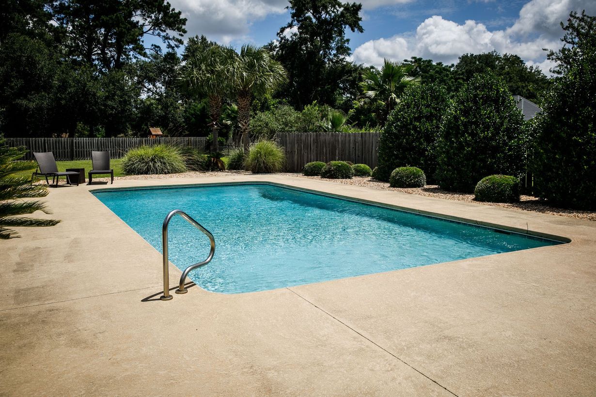 Rectangular pool with blue water and brick patio, enclosed by a screened lanai; palm trees in the background.