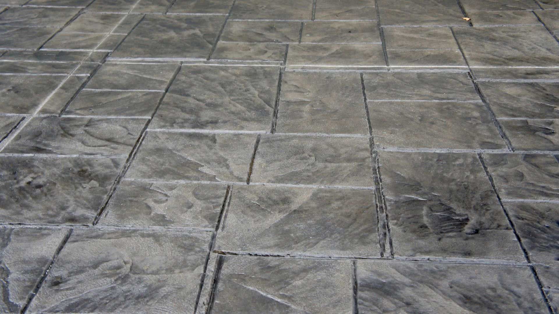 Gray stamped concrete patio with rectangular stone pattern.
