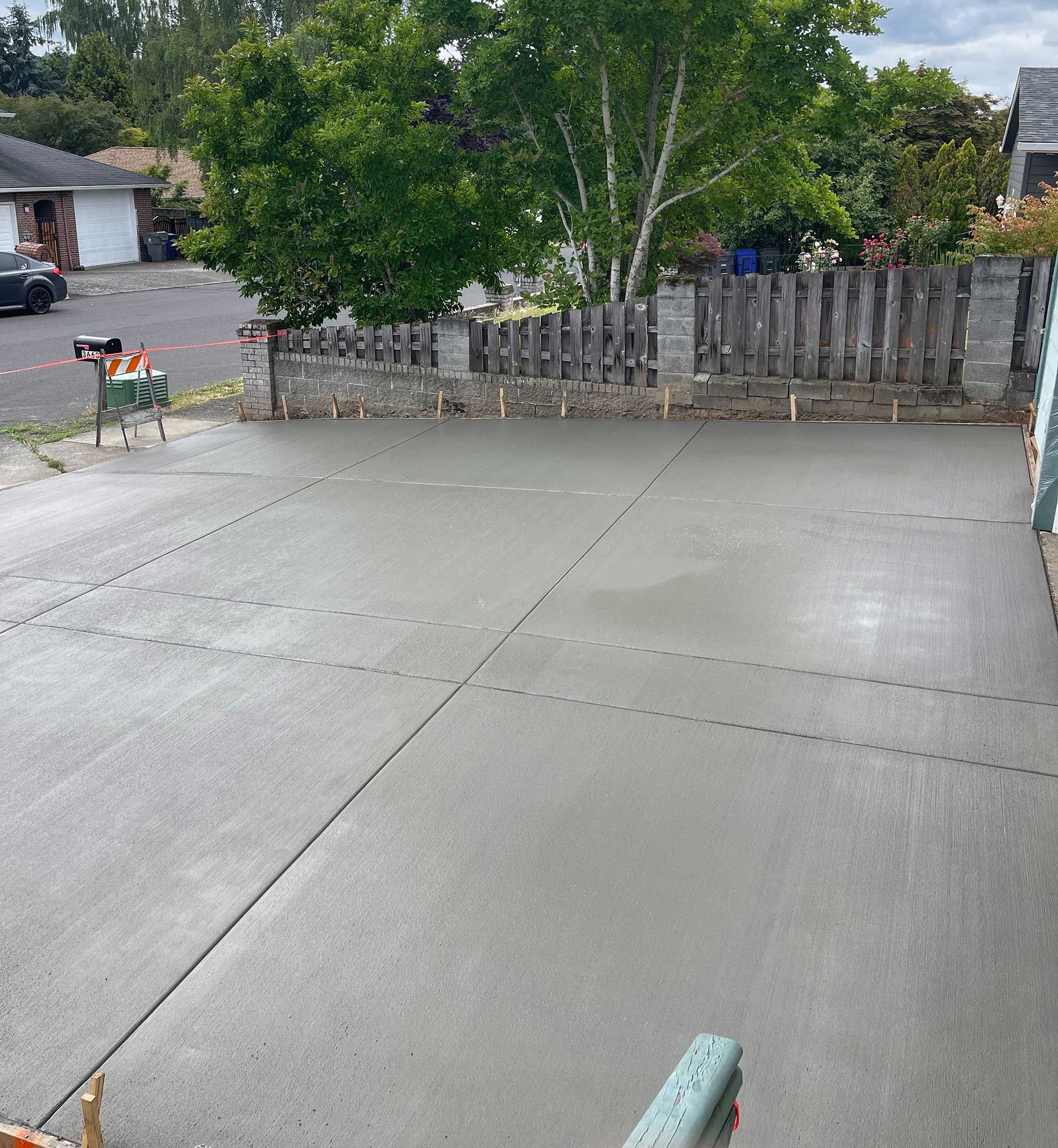Freshly poured concrete driveway, gray, with expansion joints, in front of a house.