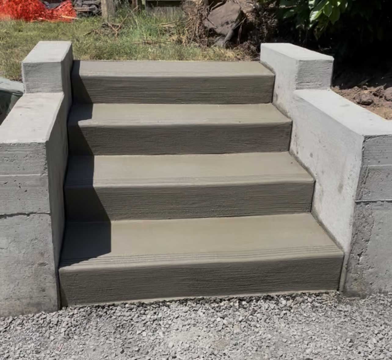 Concrete steps leading up with matching side walls. Grey construction in an outdoor setting.