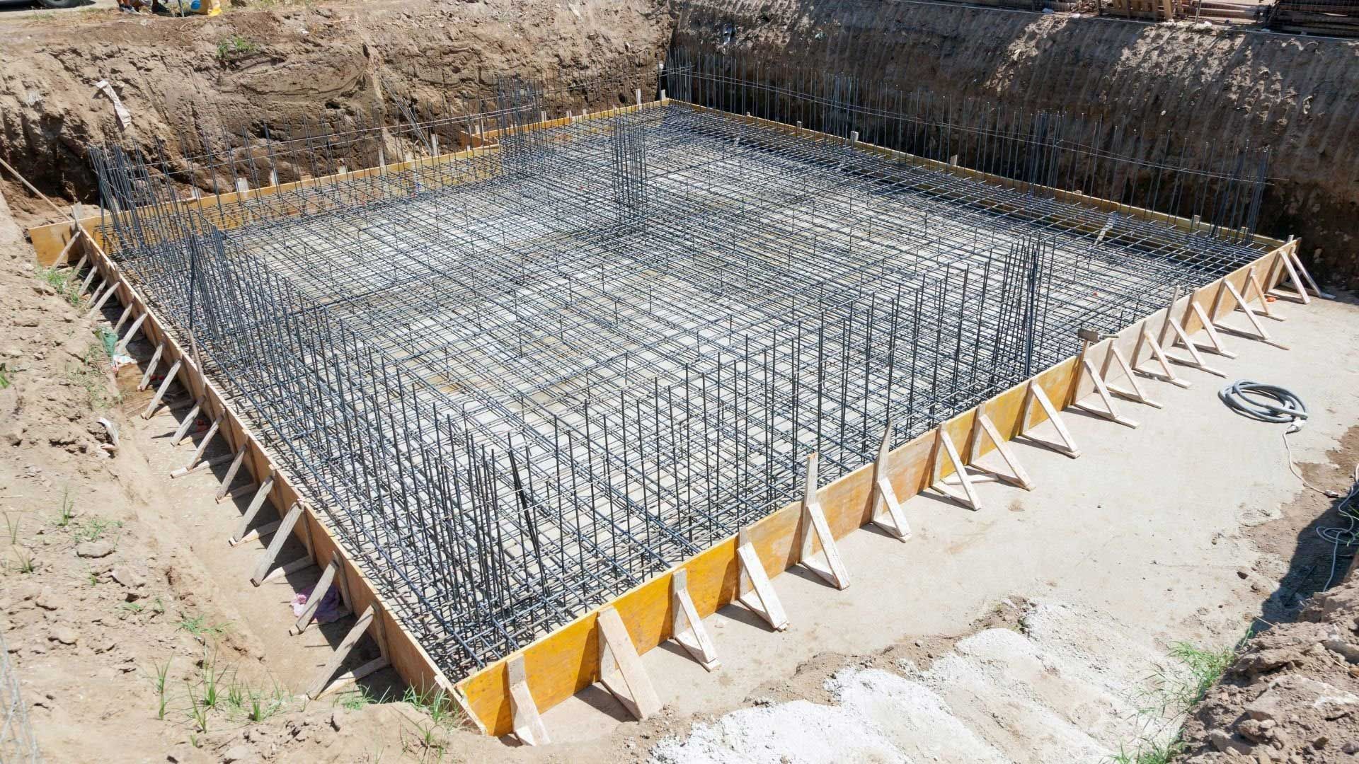 Reinforced concrete foundation formwork, including rebar, ready for pouring; outdoors.